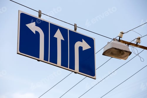 Preview: Road sign high over street with three white arrows on blue background showing direction