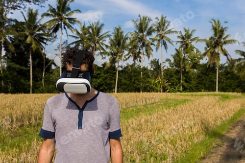 Preview: Young man with VR glasses in the tropical rice field