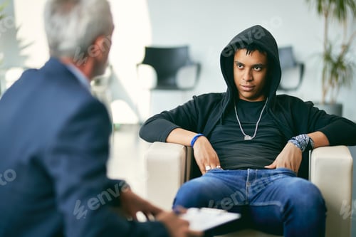 Preview: African American teenage boy having a session with mental health professional at counselling center.