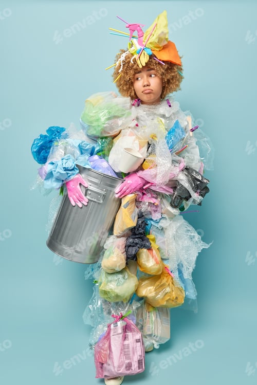 Preview: Vertical shot of unhappy curly haired woman volunteer holds rubbish bin covered with plastic garbage