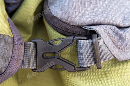 Preview: Close-up detail of locked gray convenient secure plastic clasp of yellow backpack.