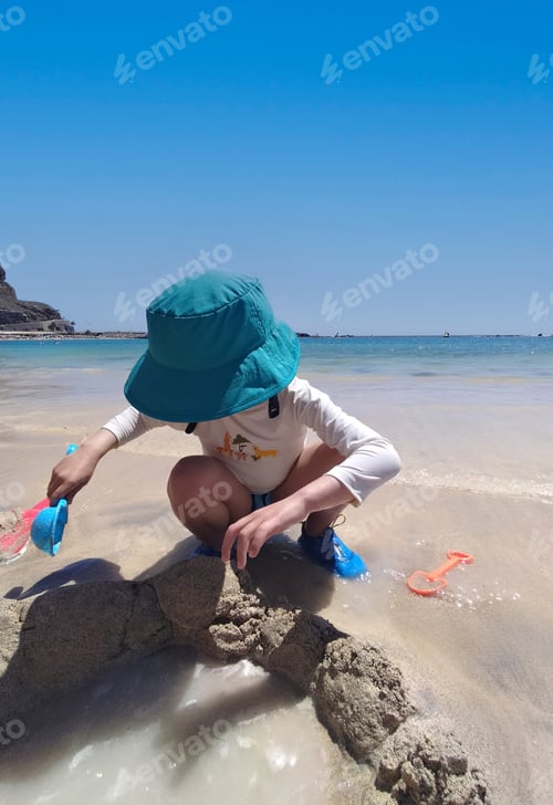 Preview: Child playing with sand on the beach on vacation