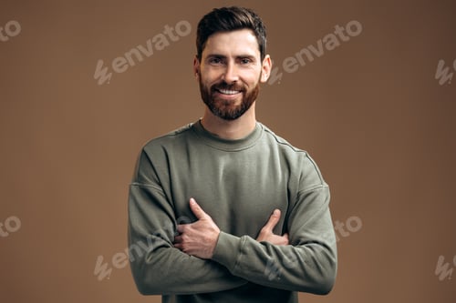 Preview: Portrait of handsome man with dark hair and beard standing with arms crossed, looking at the camera