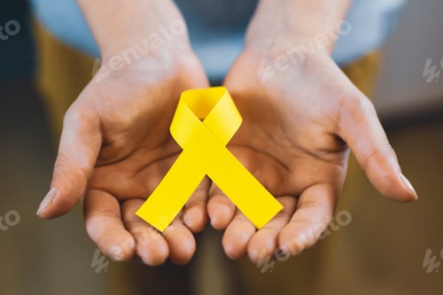 Preview: Girl hands holding yellow ribbon, childhood cancer awareness, 4 february day