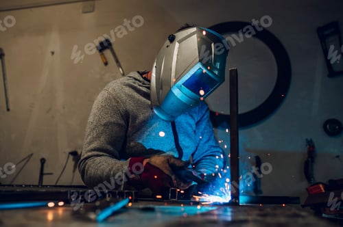 Preview: Man worker welding metal with welding machine in a factory or workshop