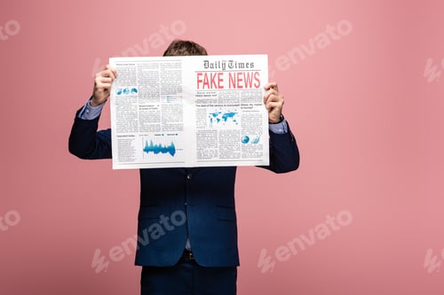 Preview: businessman holding newspaper with fake news on pink background