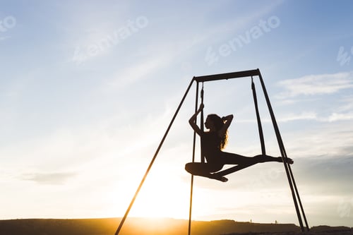 Preview: Beautiful girl practicing fly-yoga poses in a hammock outdoor at sunset