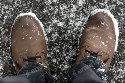 Preview: Brown boots covered with snowflakes, top view