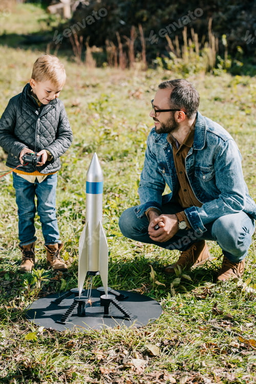 Preview: happy father and little son launching model rocket outdoor