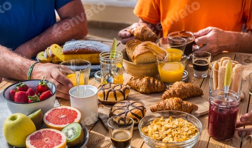 Preview: Family group having breakfast together on terrace. Wooden table with assortment of foods and fruit