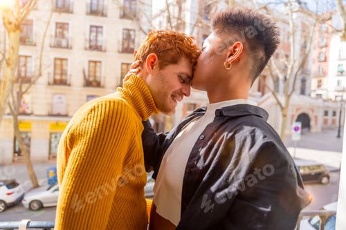 Preview: Beautiful gay couple being romantic at home on the sofa, home balcony kissing each other