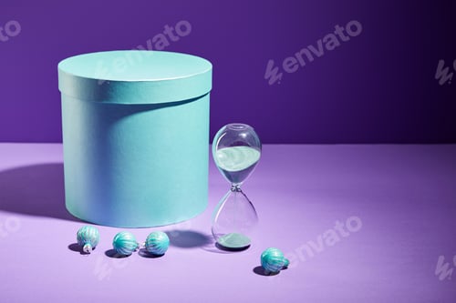 Preview: blue gift box and decorative baubles and hourglass on purple background