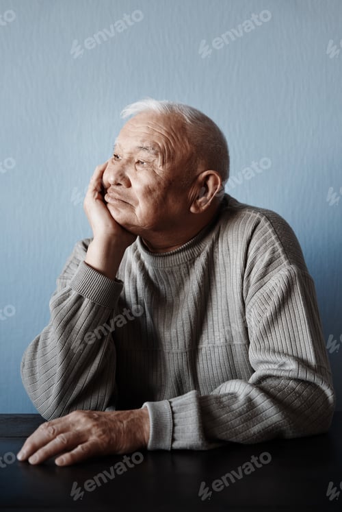 Preview: Pensive and thoughtful senior man sitting at the table