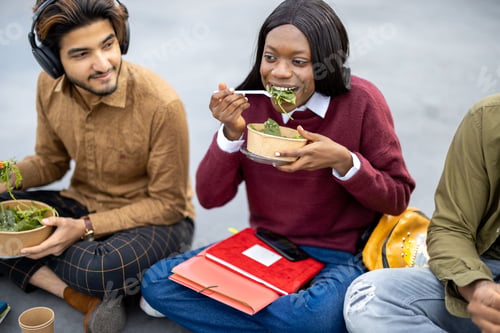 Preview: Students eating salad during lunch on asphalt