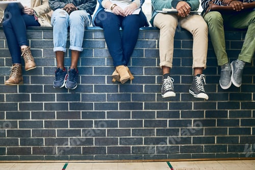 Preview: Cropped shot of a group of students sitting on a wall on campus