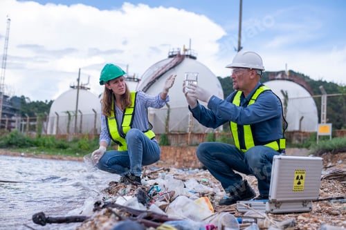 Preview: Environmental scientists or workers, wearing safety helmets and gloves, examining waste materials al