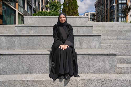 Preview: Muslim woman sitting on the parapet with her hands folded in her lap