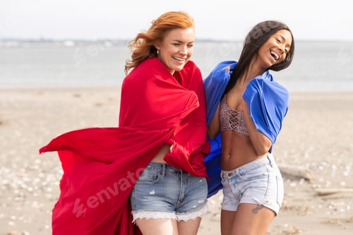 Preview: Two women playing with colorful fabric at the ocean beach