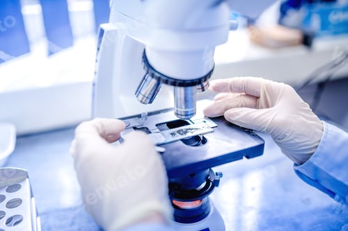 Hands Preparing Slide on Microscope in Laboratory
