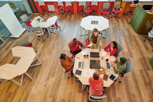 Preview: Medium group of young intercultural creative designers gathered by table