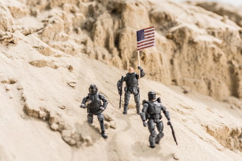Preview: toy armed soldiers standing on sand and holding american flag