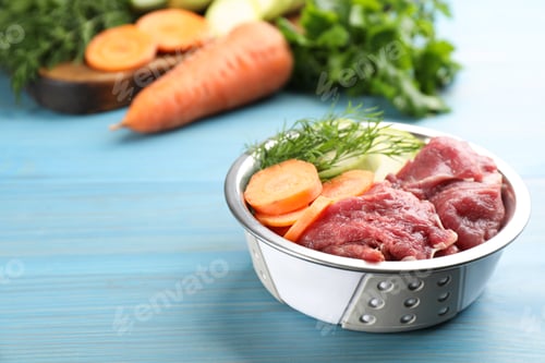 Preview: Natural pet food in feeding bowl on light blue wooden table, closeup. Space for text