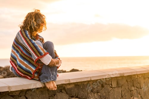 Preview: Unrecognizable lonely woman sit down on a wall looking and enjoying the sunset