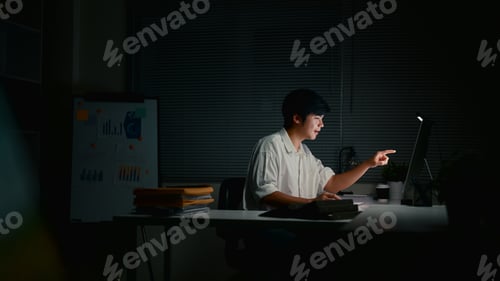 Preview: Focused businessman working late into the night, analyzing reports and entering data at computer