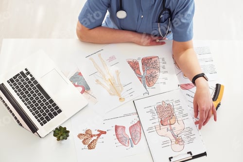 Preview: Close up view of female doctor that works by the table with pictures and laptop