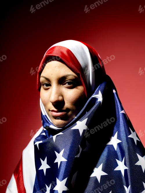 Preview: Young woman draped in an American flag hijab against a red background.