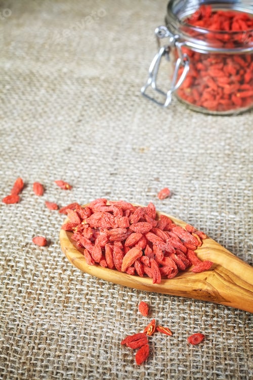Preview: Dried goji berries on a wooden spoon and linen background.