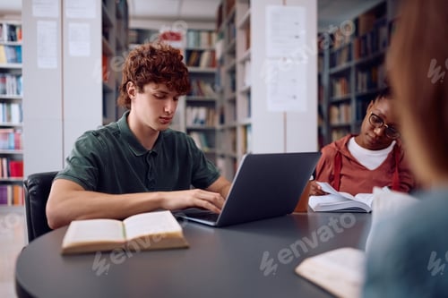 Preview: Young student e-learning on laptop while studying in library.