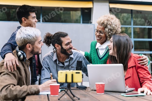 Preview: Happy digital content creators streaming live podcast online using microphone and laptop outdoors