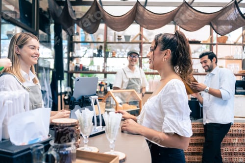 Preview: Caucasian attractive women receive coffee from waiter in coffee house.
