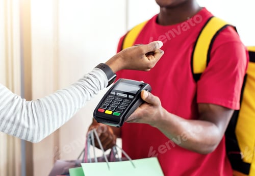 Preview: African Female Paying Courier With Smartwatch Receiving Shopping Bags Indoor