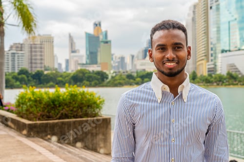 Preview: Handsome young black businessman at park outdoors during summer