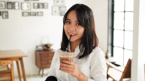 Preview: Beautiful asian business in suit standing holding brown coffee cup in caffe having a coffee break.