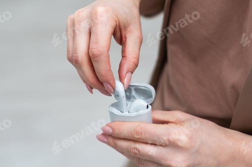 Preview: Hand holding Grey wireless headphones isolated on a white background.
