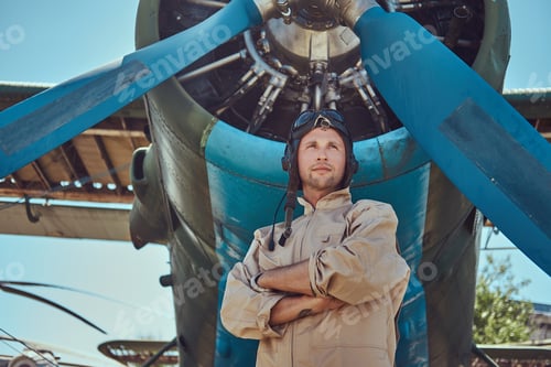 Preview: Pilot or mechanic in a full flight gear next to retro military aircraft