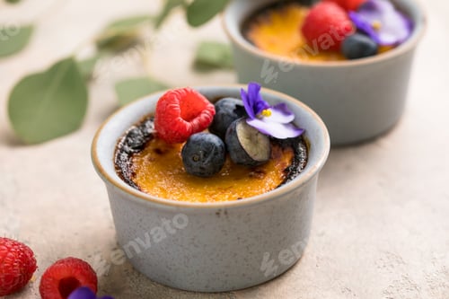 Preview: Creme brulee. French vanilla cream dessert with caramelised sugar and berries, selective focus.