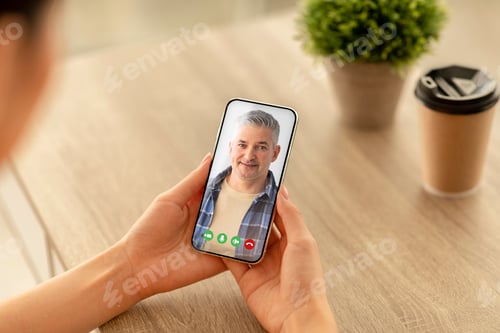 Preview: Young female holding cellphone in hand making video call