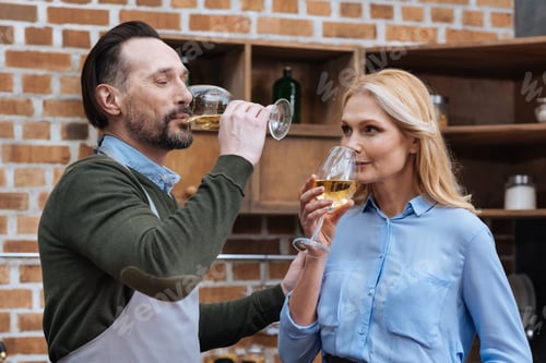 Preview: husband and wife drinking wine from glasses in kitchen