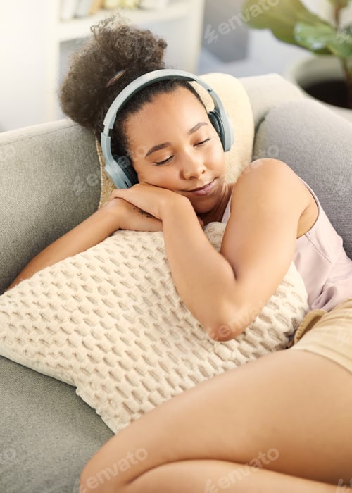 Preview: Dont fight the sleep. Shot of a young woman listening to music while relaxing at home.