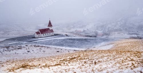 Preview: Vik I Myrdal church at the top of the hill during heavy snow at the village of Vik in Iceland in