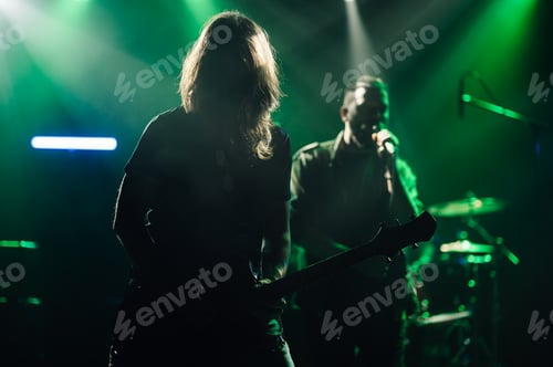 Preview: Guitarist and singer performing on stage under green lights