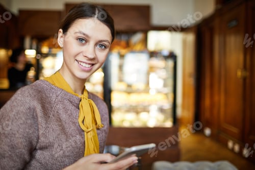 Smiling Woman Using Smartphone in Cozy Cafe