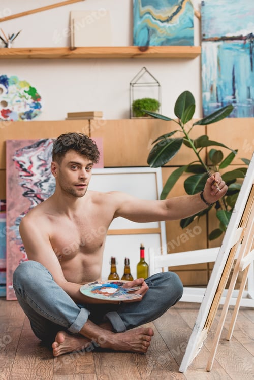 Preview: handsome half-naked artist holding palette and painting picture on canvas