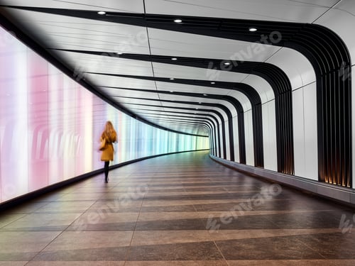 Preview: Rear view of woman walking through tunnel walkway, London City Airport, London, UK