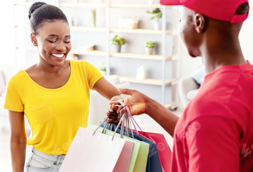 Preview: African Lady Receiving Shopping Bags From Delivery Man At Home
