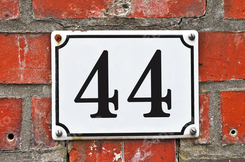 Preview: Closeup of a board showing numbers on the apartment building on a brick wall